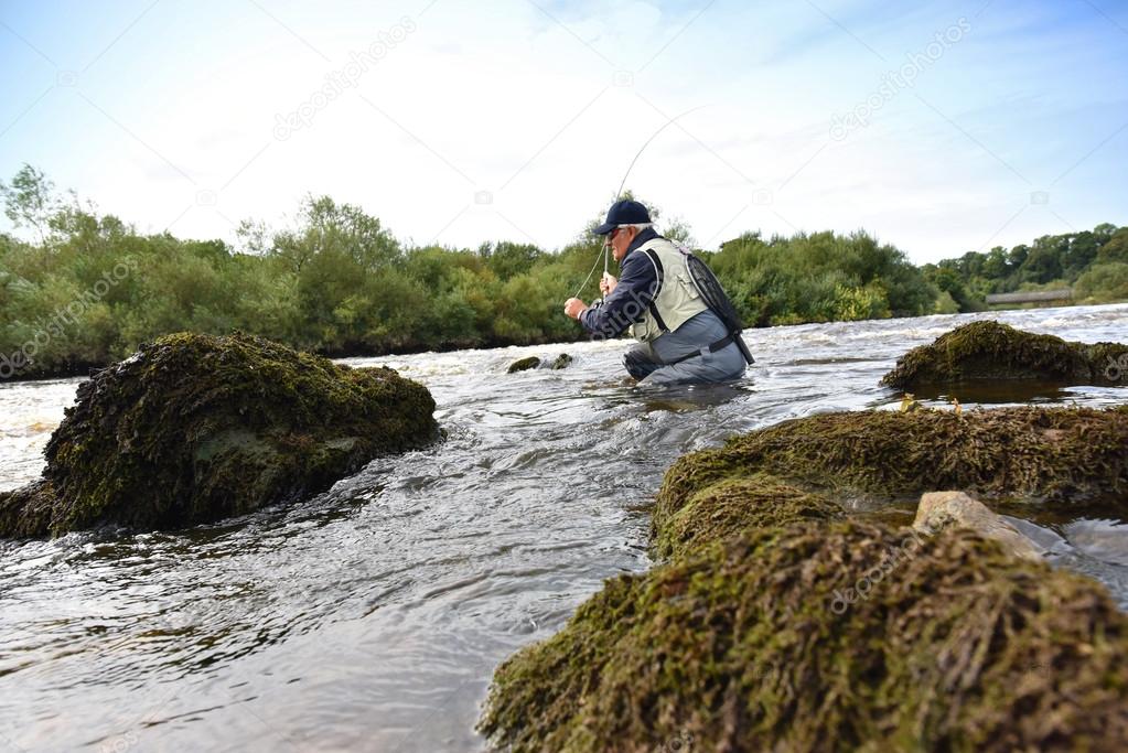 Fly fisherman fishing in river