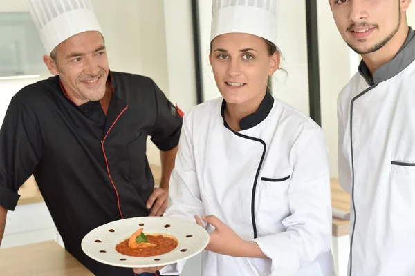 Chefs presenting dish to teacher — Stock Photo, Image