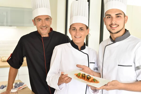 Chefs presenting dish to teacher — Stock Photo, Image