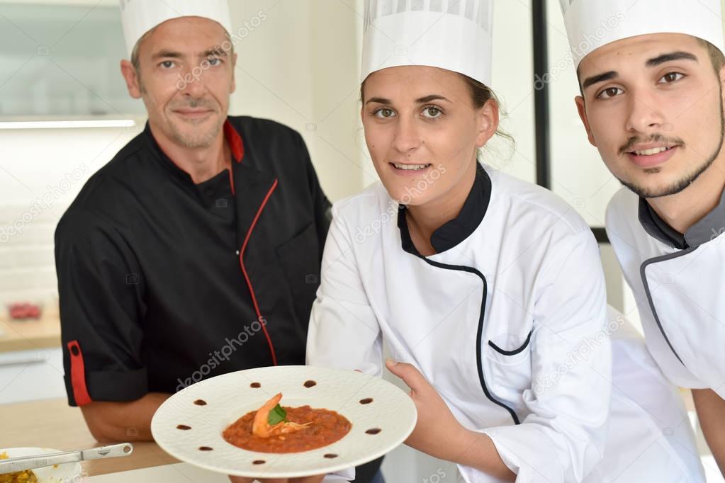  chefs presenting dish to teacher
