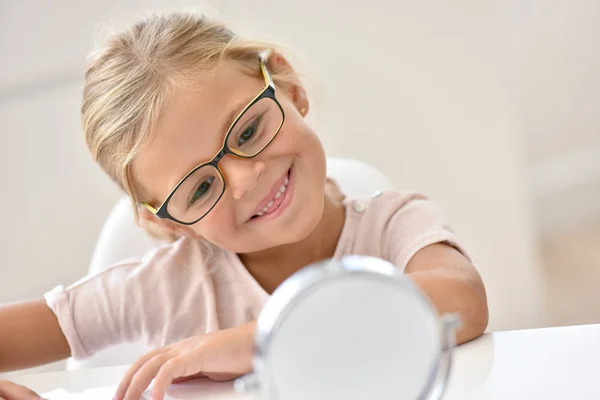 Menina no óptico tentando óculos — Fotografia de Stock