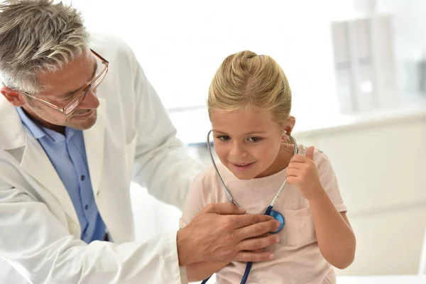 Chica en el médico, usando estetoscopio — Foto de Stock