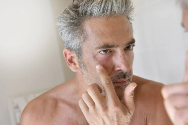 Homem na frente do espelho aplicando creme — Fotografia de Stock