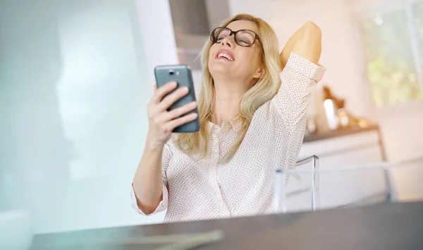 Женщина в офисе с помощью смартфона — стоковое фото