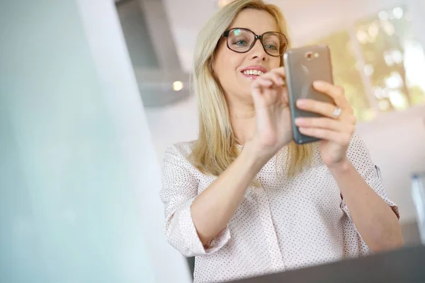 Женщина в офисе с помощью смартфона — стоковое фото