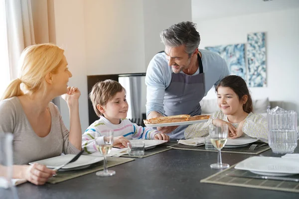 Dad serving pizza to family