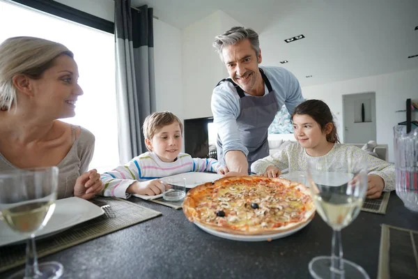 Папа подает пиццу семье — стоковое фото