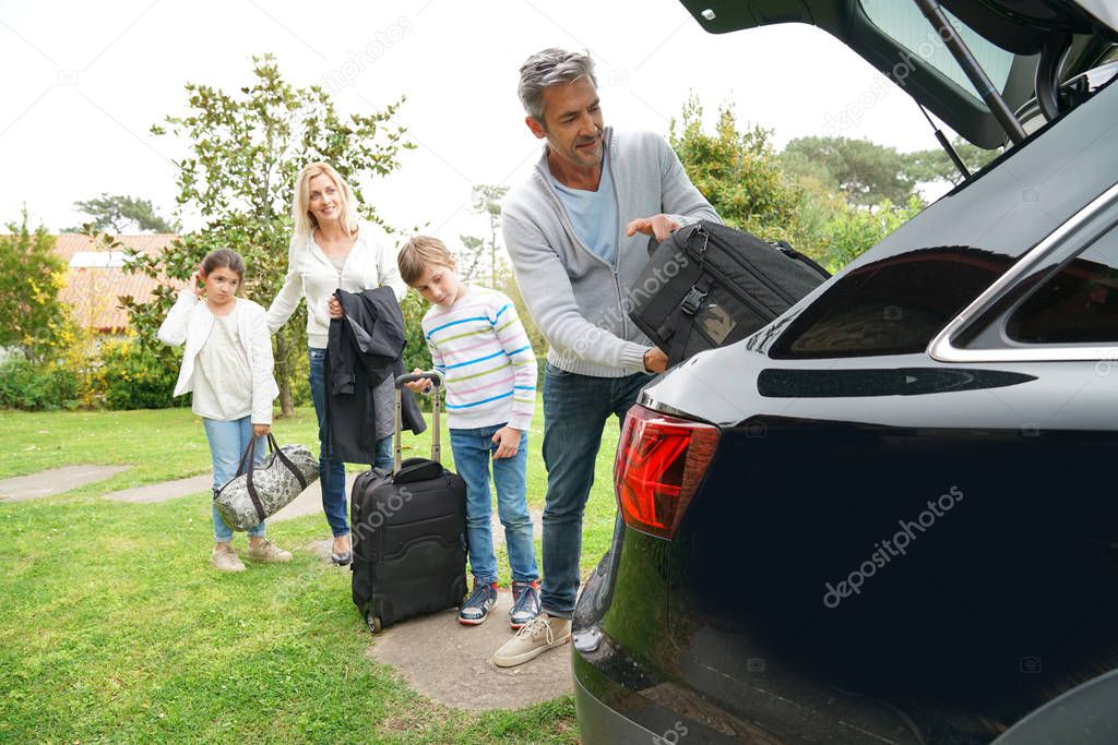 Family packing suitcases in car