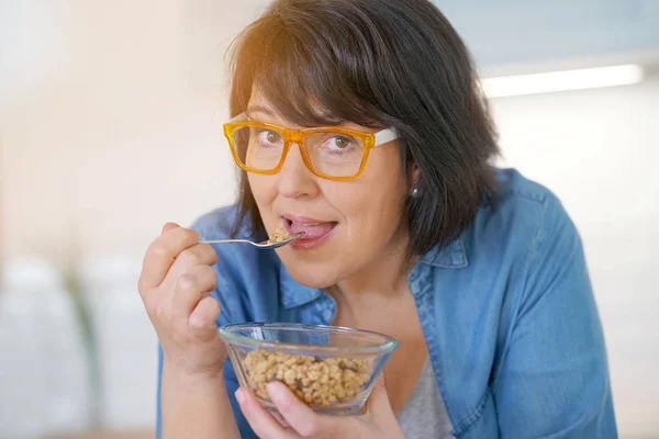 Mulher na cozinha comer cereais — Fotografia de Stock