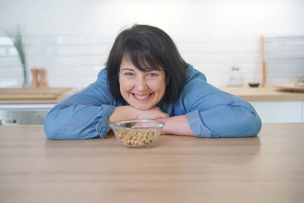 Женщина на кухне ест крупы — стоковое фото