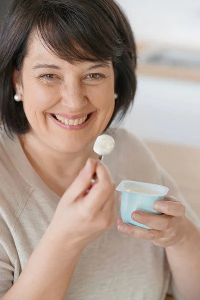 Mature woman eating yogurt — Stock Photo, Image