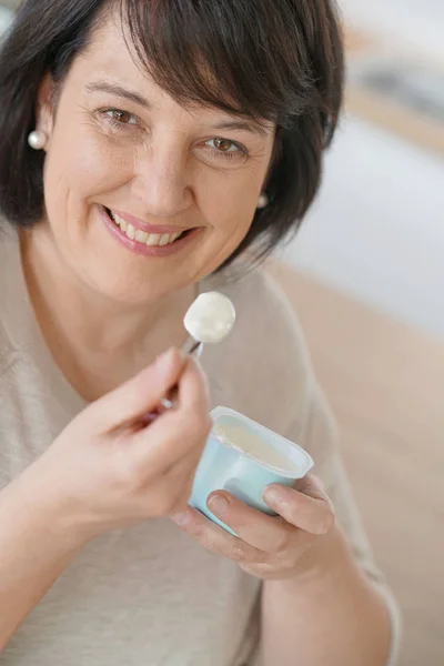 Mature woman eating yogurt — Stock Photo, Image