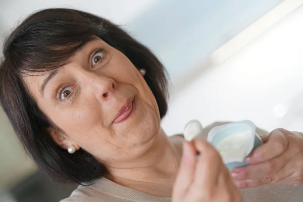 Mature woman eating yogurt — Stock Photo, Image