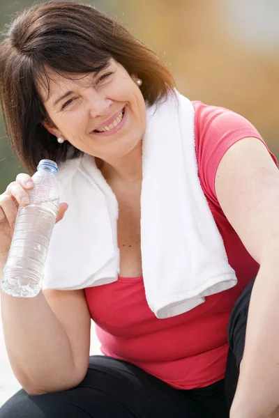 Mulher em roupa fitness segurando água — Fotografia de Stock