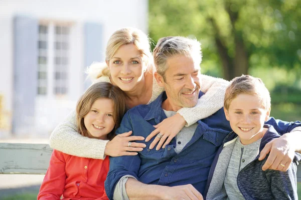 Vierköpfige Familie sitzt auf Bank — Stockfoto