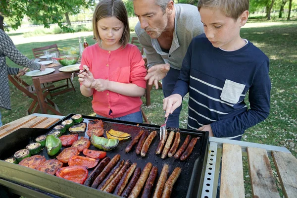 Отец с детьми готовит барбекю — стоковое фото