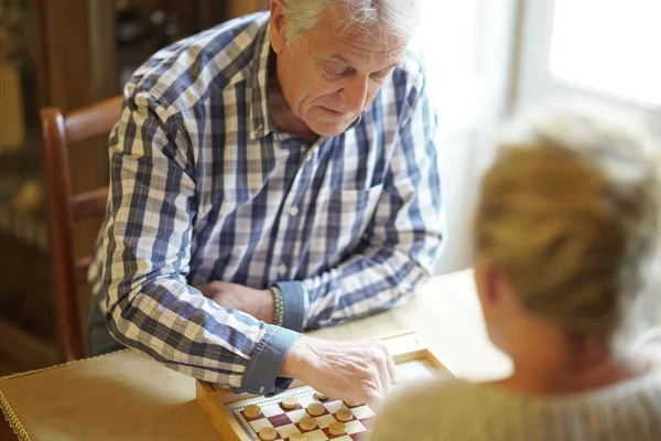 Seniorenpaar spielt Dame — Stockfoto