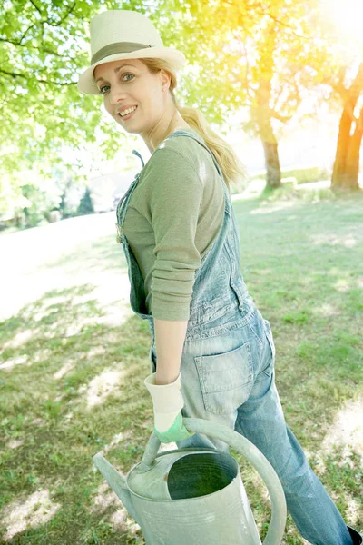 Mulher no jardim segurando rega pode — Fotografia de Stock