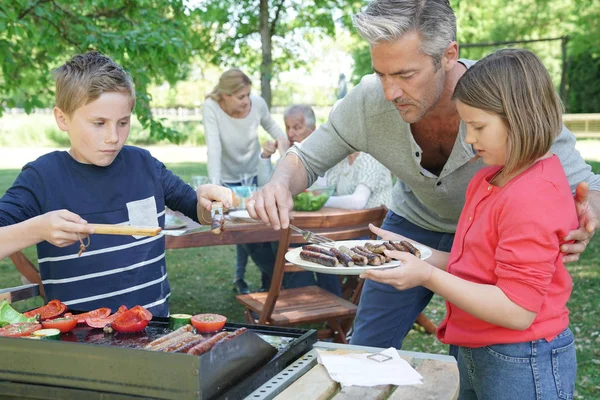 Pai com crianças preparando churrasco — Fotografia de Stock