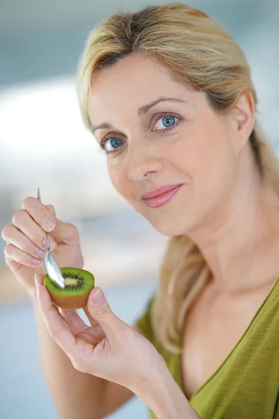 Blond kvinna äta kiwi — Stockfoto