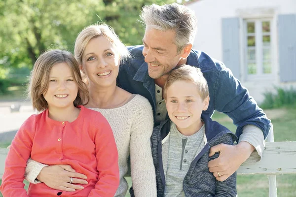 Family of four sitting on bench — Stock Photo, Image