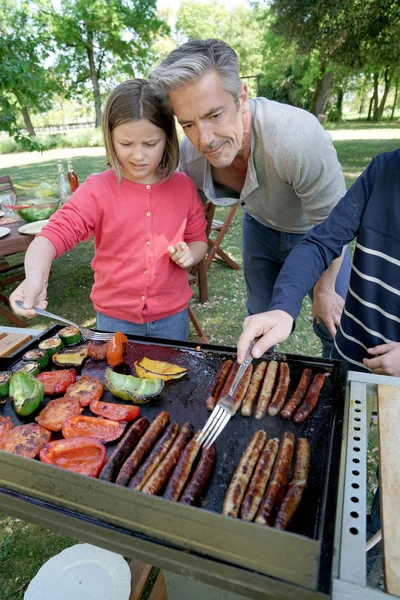 Padre con i bambini preparare barbecue Immagine Stock