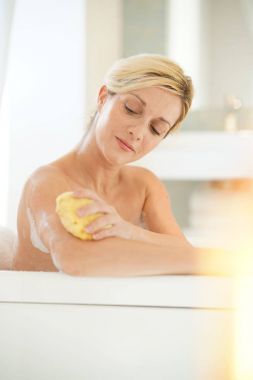 Banyo süngeri kullanan kadın.