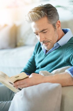 Evde birkaç kitap, adam ön planda okuma