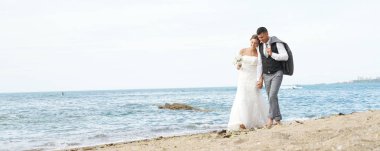 Gelin ve damat sahilde yürüyor.