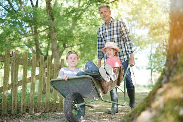 Papa riding kinderen in kruiwagen — Stockfoto