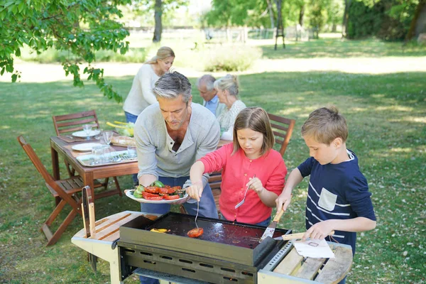Homem com crianças cozinhar churrasco — Fotografia de Stock