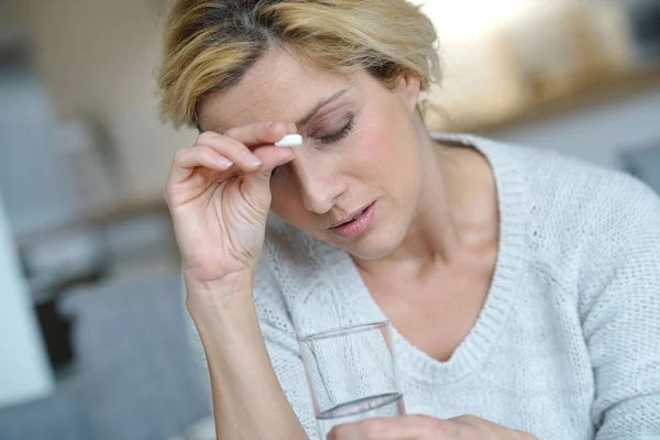 Frau zu Hause nimmt Tablette — Stockfoto