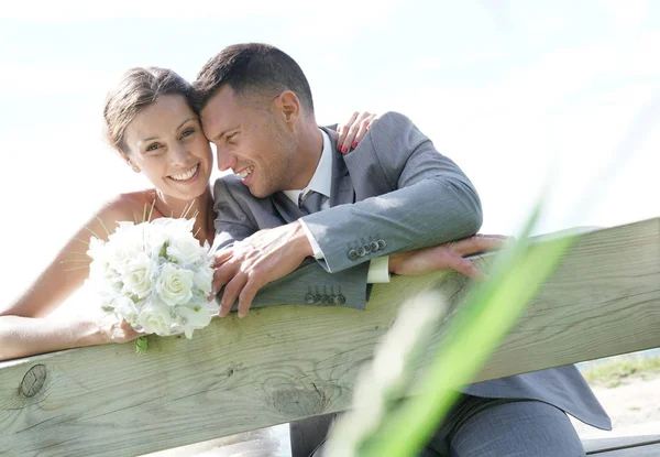 Bruden och brudgummen lutande på staket — Stockfoto
