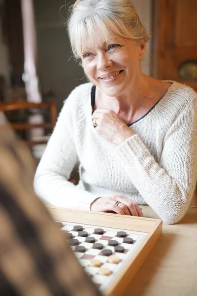 Senior couple playing checkers — Stock Photo, Image