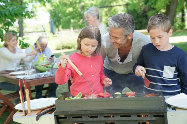 Pai com crianças preparando churrasco — Fotografia de Stock