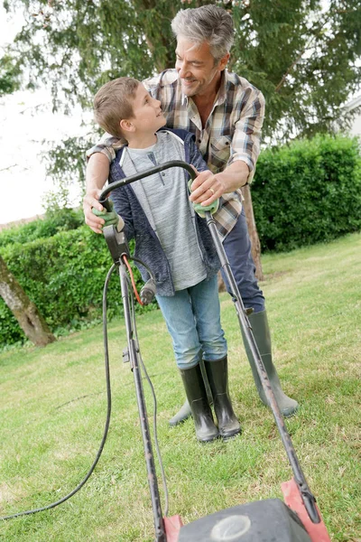 Vader en zoon maaien gazon — Stockfoto