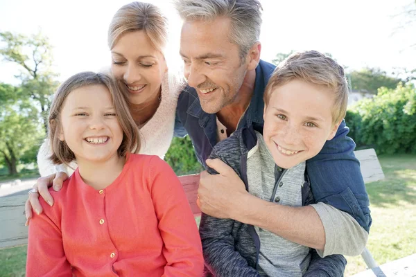 Familj på fyra sitter på bänk — Stockfoto