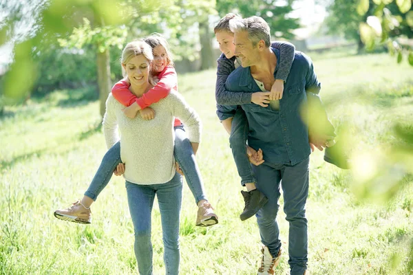 Föräldrar ger piggyback rida till barnen jag — Stockfoto