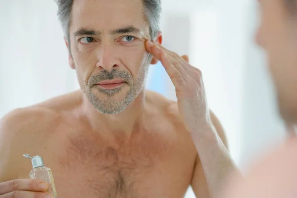 Hombre maduro aplicando crema facial — Foto de Stock
