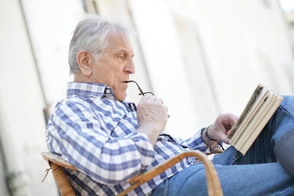 Elderly man reading book outside