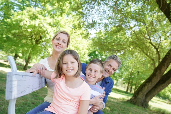 Счастливая семья сидит на скамейке — стоковое фото