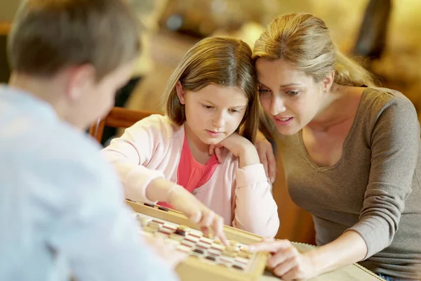 Mother with kids playing checkers — Stock Photo, Image