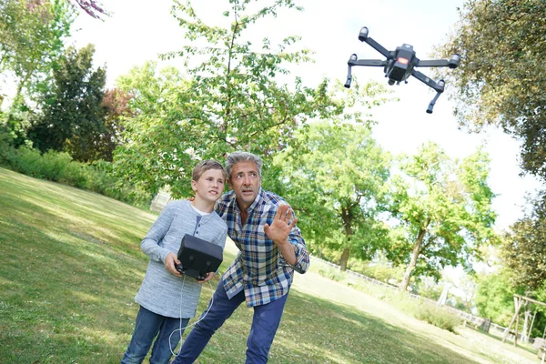 Отец и сын играют с летающим дроном — стоковое фото