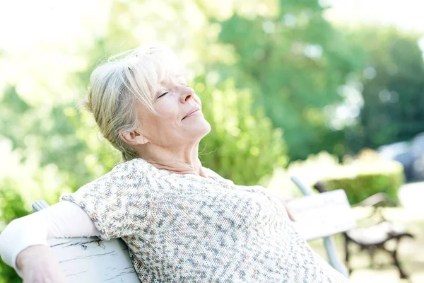 Senior woman relwing on bench — Stock Photo, Image