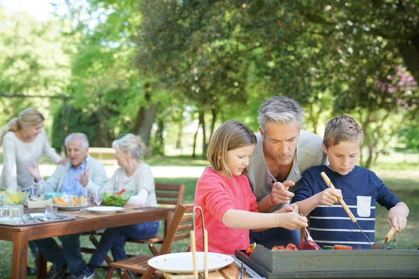 Man met kinderen koken barbecue — Stockfoto