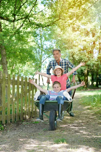 Daddy riding kids in wheelbarrow — Stock Photo, Image