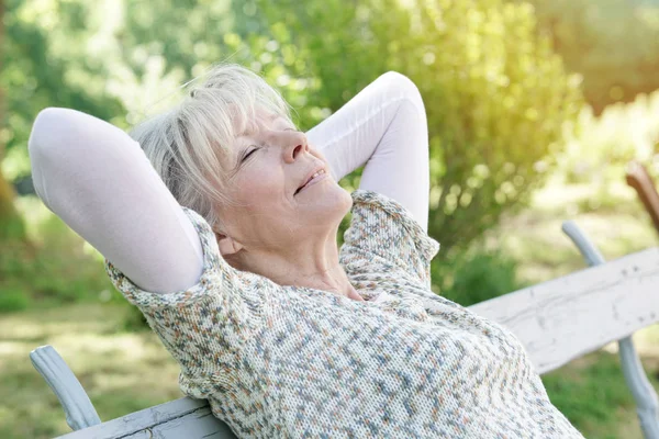Senior woman relwing on bench — Stock Photo, Image