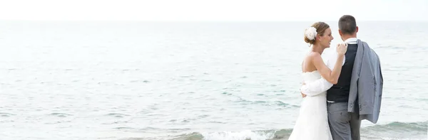 Bruid en bruidegom permanent op het strand — Stockfoto