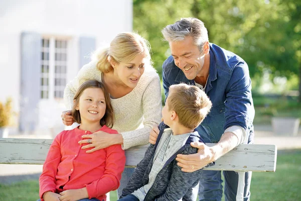 Family of four sitting on bench — Stock Photo, Image