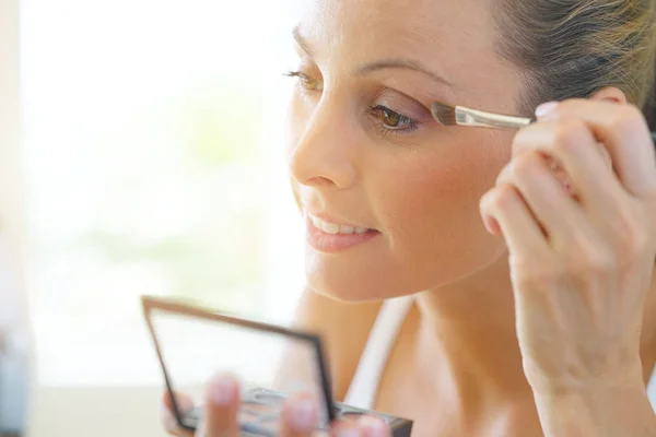 Mujer aplicando sombra de ojos en — Foto de Stock